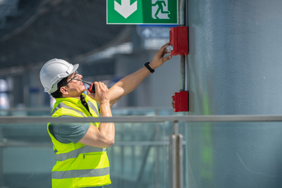 construction worker checking safety alarm system in building emergency exit location for compliance with safety protocols and regulations 11 safety standards building navigation