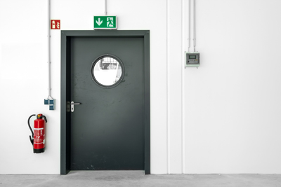 green door with circular window fire extinguisher and emergency exit sign ten safety features and precautions